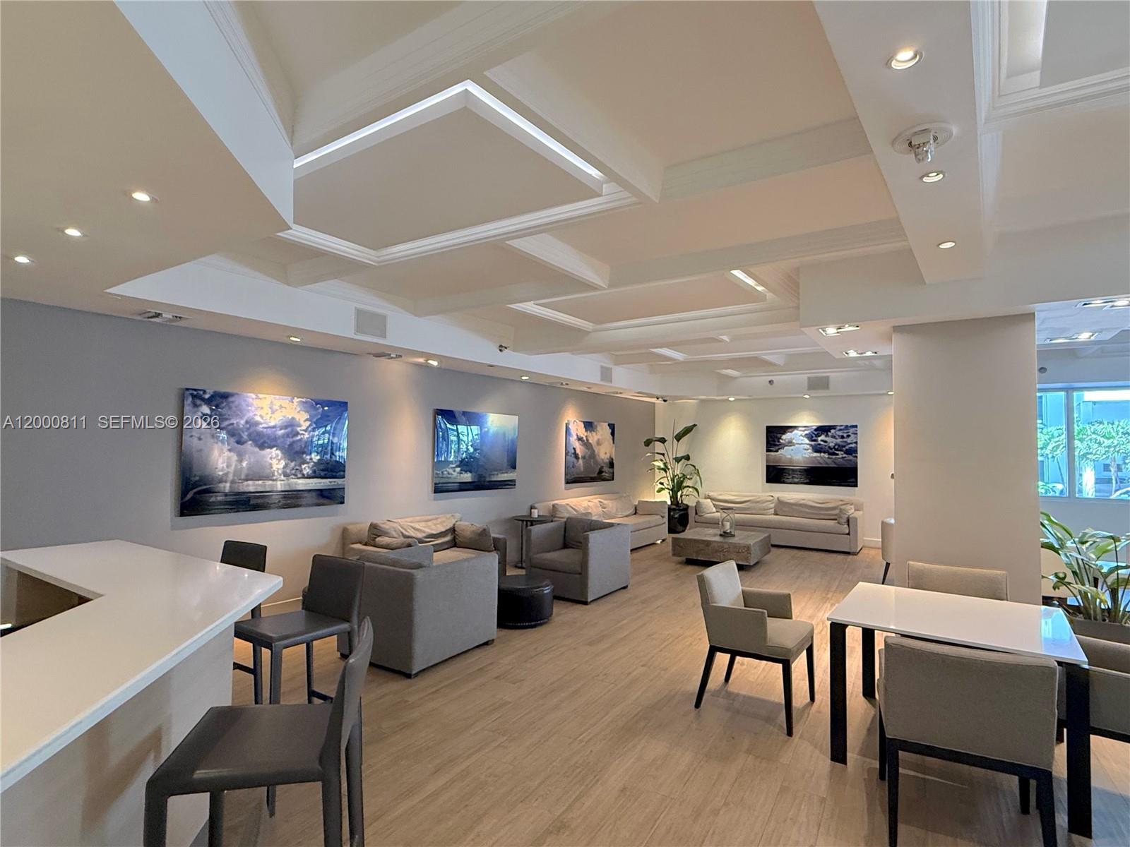 A modern, open-plan lounge area features gray seating, artwork, and a coffered ceiling — 100 Lincoln Rd # 1405, Miami Beach FL 33139, MIAMI BEACH, FL