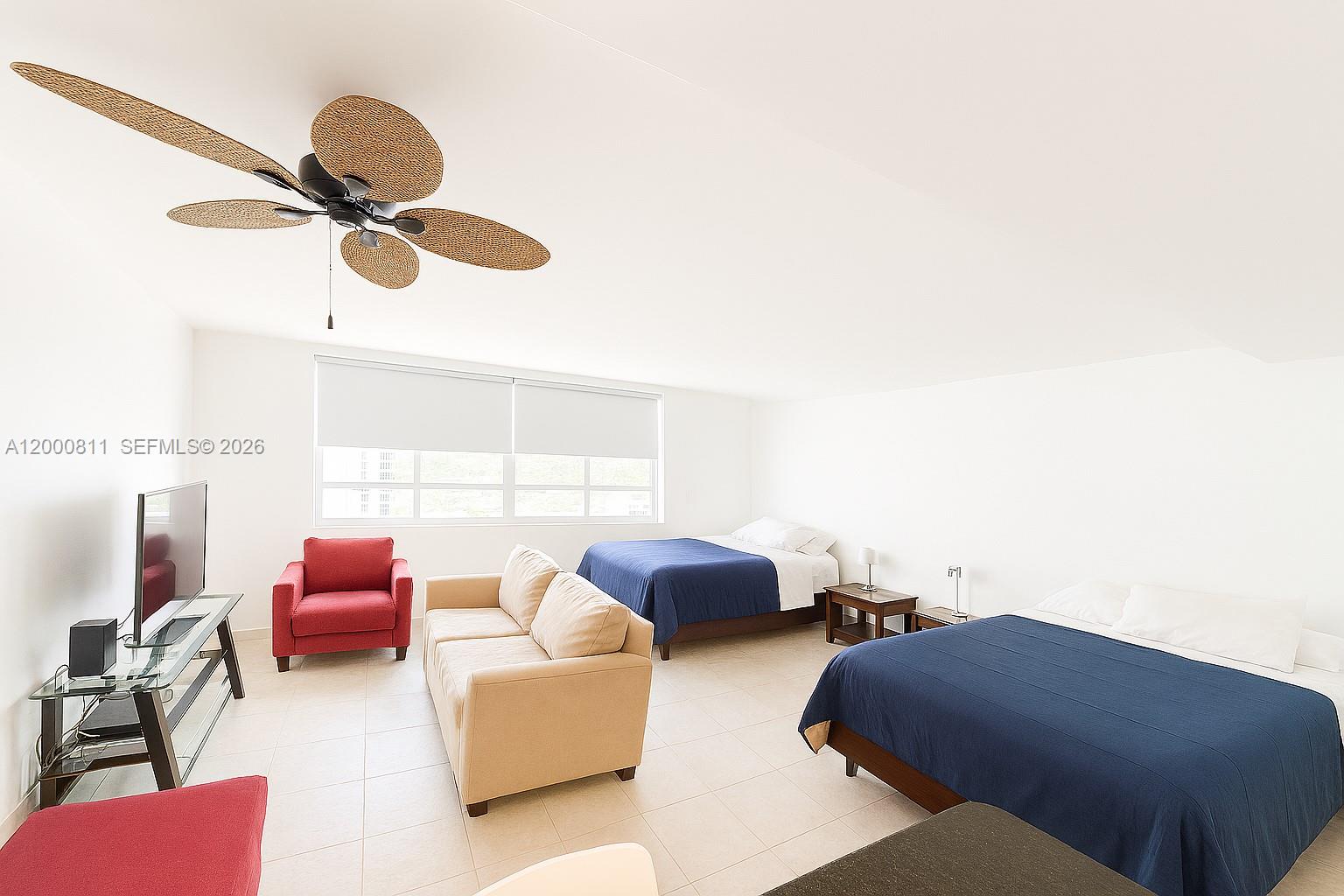 A bedroom features two beds, a sofa, a red armchair, and a ceiling fan — 100 Lincoln Rd # 1405, Miami Beach FL 33139, MIAMI BEACH, FL