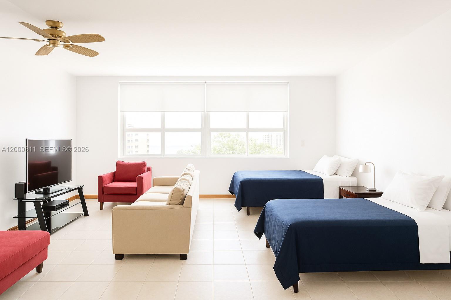 A bedroom with two beds, a sofa, a red armchair, and a television — 100 Lincoln Rd # 1405, Miami Beach FL 33139, MIAMI BEACH, FL