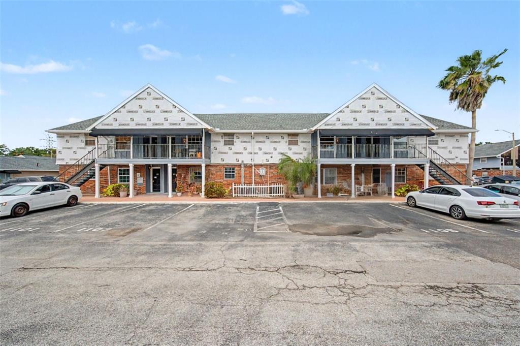 A two-story apartment building exterior features exposed sheathing, brick ground level, and a parking lot — 200 COUNTRY CLUB DRIVE UNIT 1101, LARGO, FL