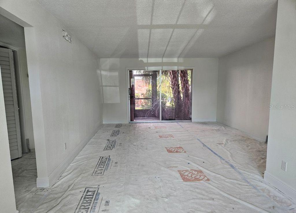 An empty room with white walls, a sliding glass door, and protective floor covering — 200 COUNTRY CLUB DRIVE UNIT 1101, LARGO, FL