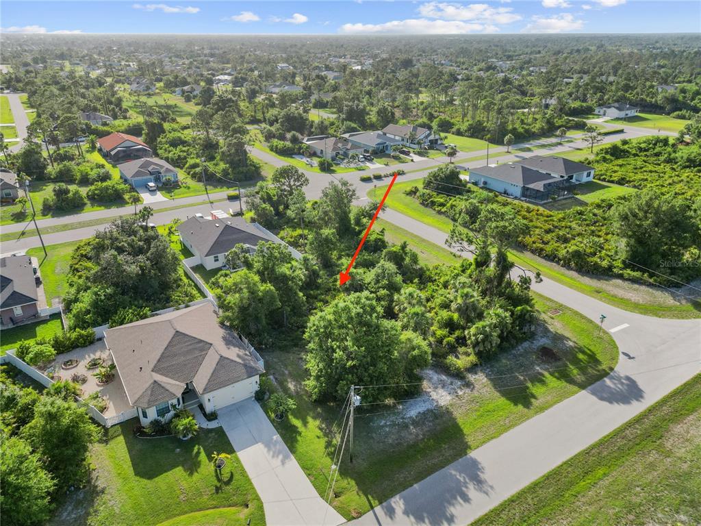 An aerial view shows a vacant, tree-covered residential lot situated between two suburban houses — 168 WHITE PINE DRIVE, ROTONDA WEST, FL