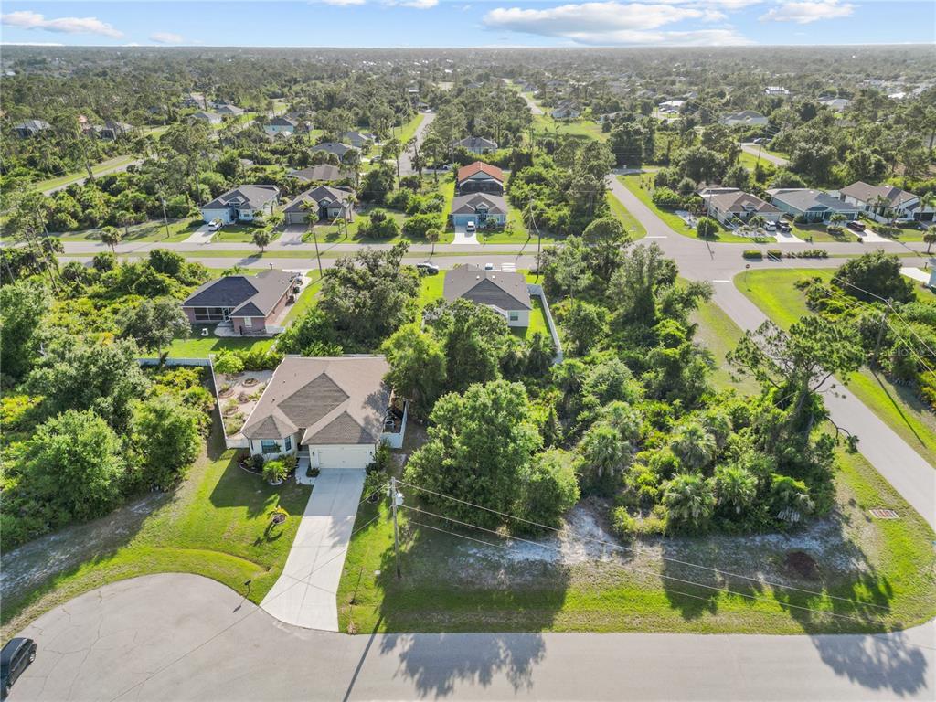 An aerial view shows a suburban house with a driveway in a wooded neighborhood — 168 WHITE PINE DRIVE, ROTONDA WEST, FL