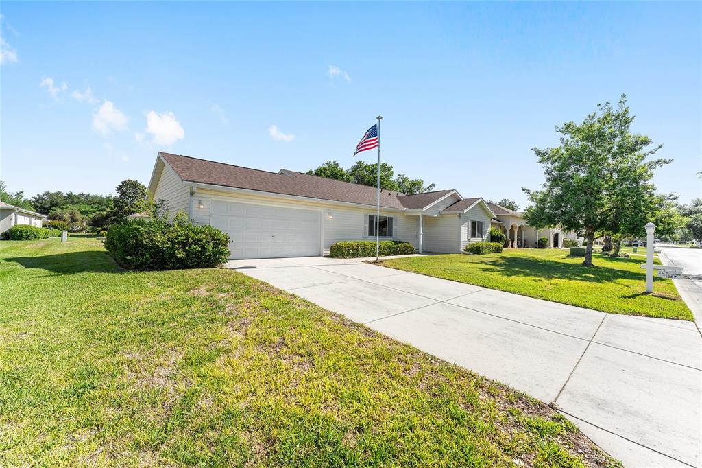 A single-story house with a beige exterior, a two-car garage, and an American flag — 11587 SW 139TH PLACE, DUNNELLON, FL