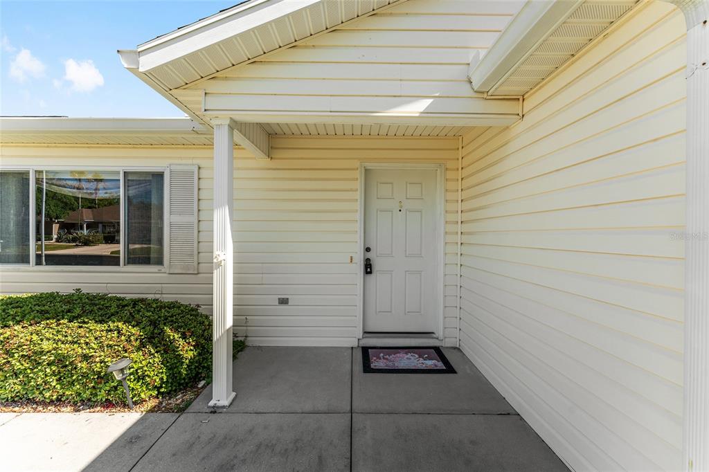 A white front door with six panels is set under a covered porch with siding — 11587 SW 139TH PLACE, DUNNELLON, FL