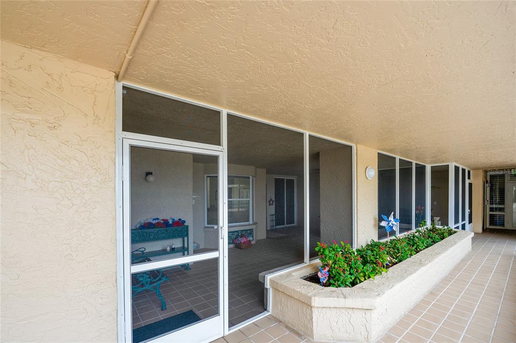 A covered patio features a screened enclosure, tiled flooring, and a built-in concrete planter — 4565 S ATLANTIC AVENUE UNIT 5407, PORT ORANGE, FL