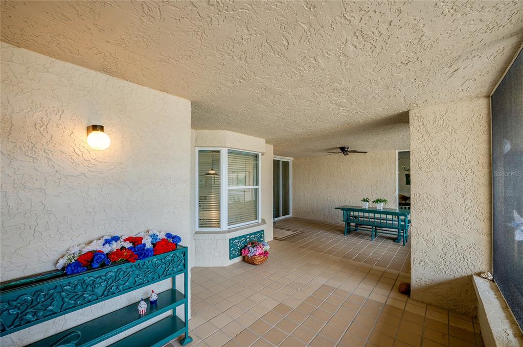 A covered patio features tiled flooring, a teal metal shelf, and a dining set — 4565 S ATLANTIC AVENUE UNIT 5407, PORT ORANGE, FL