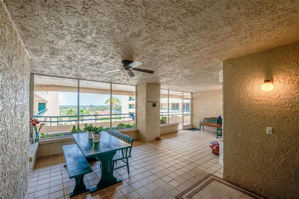 A covered balcony features a dining table, tile flooring, a ceiling fan, and exterior views — 4565 S ATLANTIC AVENUE UNIT 5407, PORT ORANGE, FL