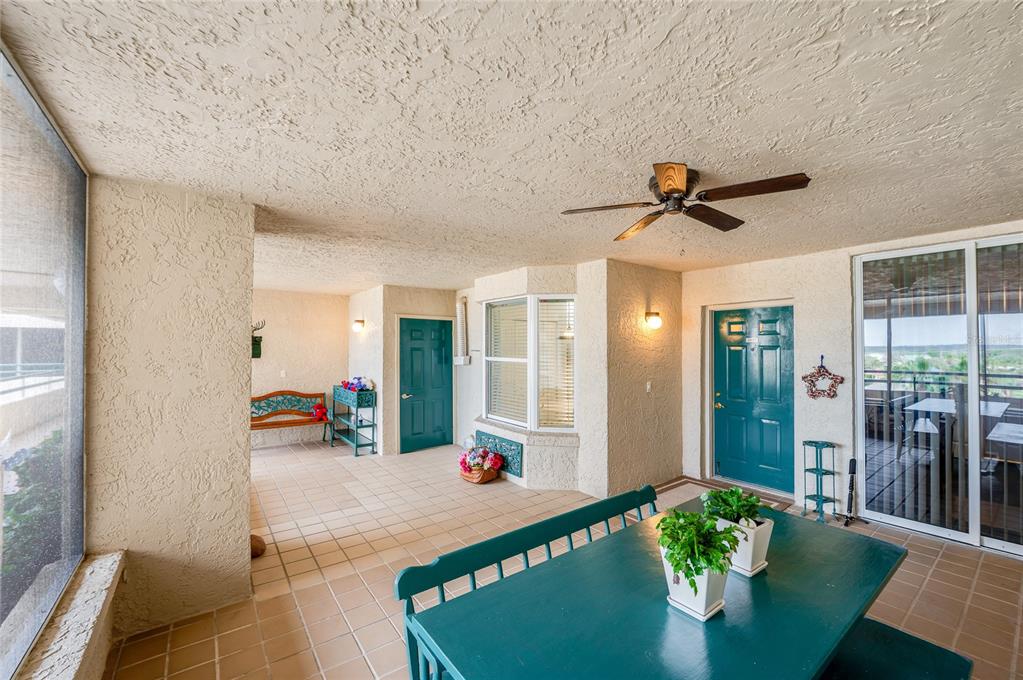 A covered patio features tile flooring, a ceiling fan, and two teal doors — 4565 S ATLANTIC AVENUE UNIT 5407, PORT ORANGE, FL