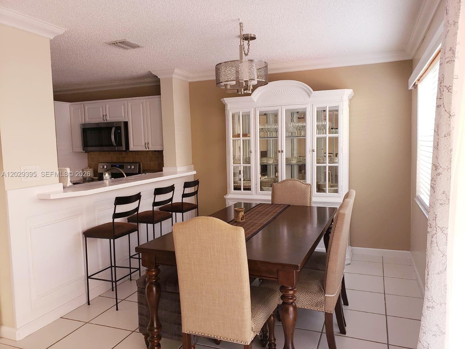 A dining room with a wooden table, chairs, and a white hutch near a kitchen — 223 Maple Ter, Davie FL 33325, DAVIE, FL