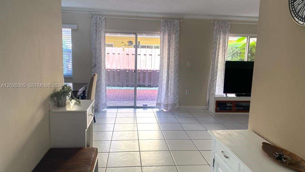 A living room features white tile floors, a sliding glass door, and a television console — 223 Maple Ter, Davie FL 33325, DAVIE, FL