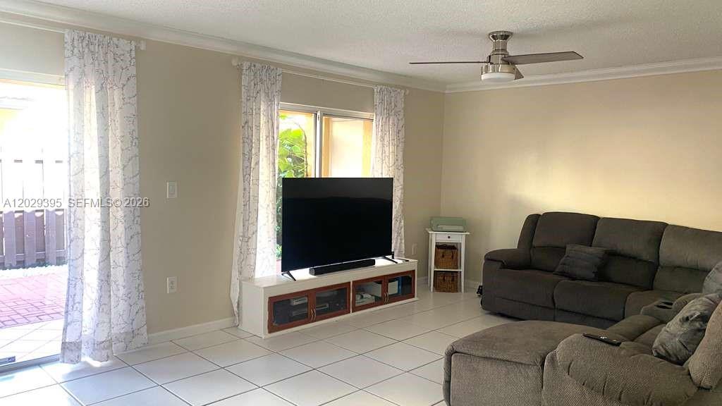 A living room features a gray sectional sofa, a television on a stand, and tile flooring — 223 Maple Ter, Davie FL 33325, DAVIE, FL