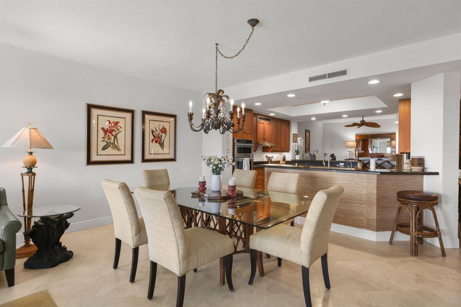 A dining room with a glass table, upholstered chairs, and an adjacent kitchen with bar seating — 500 S Us Highway 1 # 202, Jupiter FL 33477, JUPITER, FL