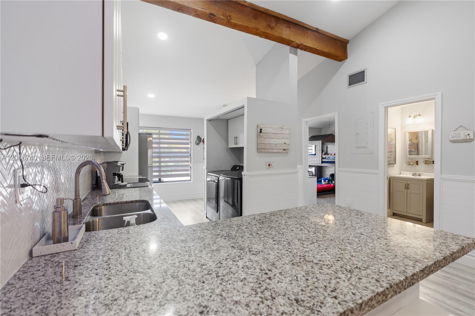 A kitchen with granite countertops and a sink overlooks a laundry area and two doorways — 10311 Laurel Ct, Pembroke Pines FL 33026, PEMBROKE PINES, FL