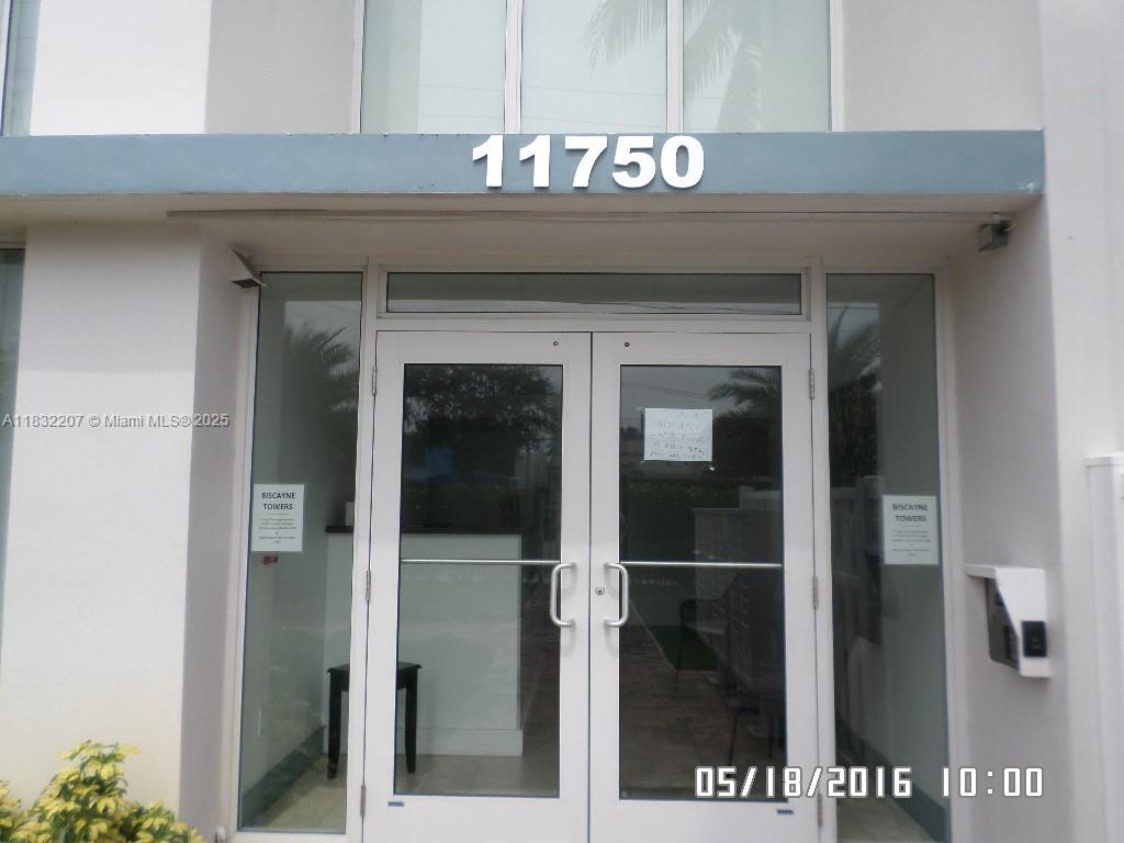 The exterior entrance of a building features double glass doors under the number 11750 — 11750 NE 16th Ave # 102, Miami FL 33161, MIAMI, FL