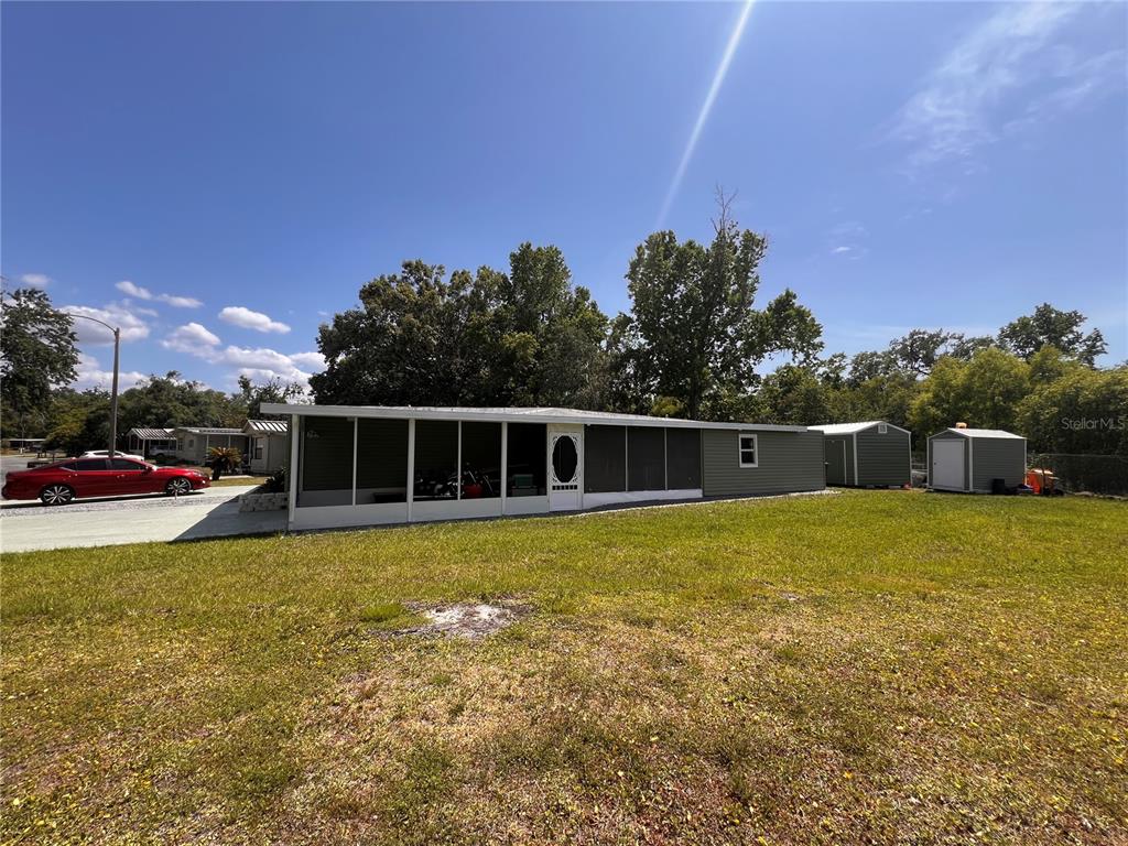 A single-story mobile home with a screened-in porch and two detached sheds in the yard — 7291 WINDY WAY, BROOKSVILLE, FL