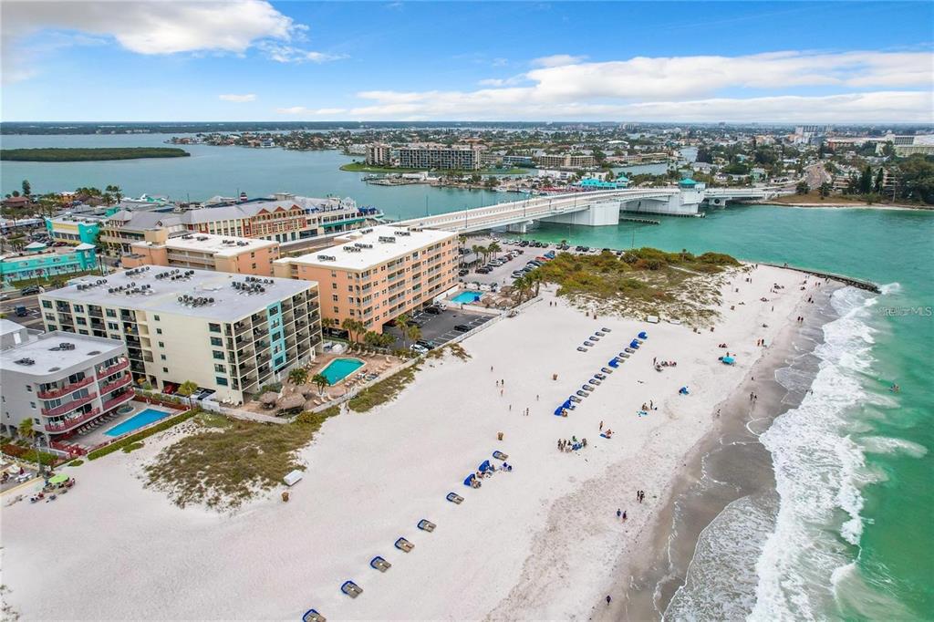 An aerial view of a beach with hotels, a swimming pool, and a bridge nearby — 12924 GULF BOULEVARD UNIT 510, MADEIRA BEACH, FL