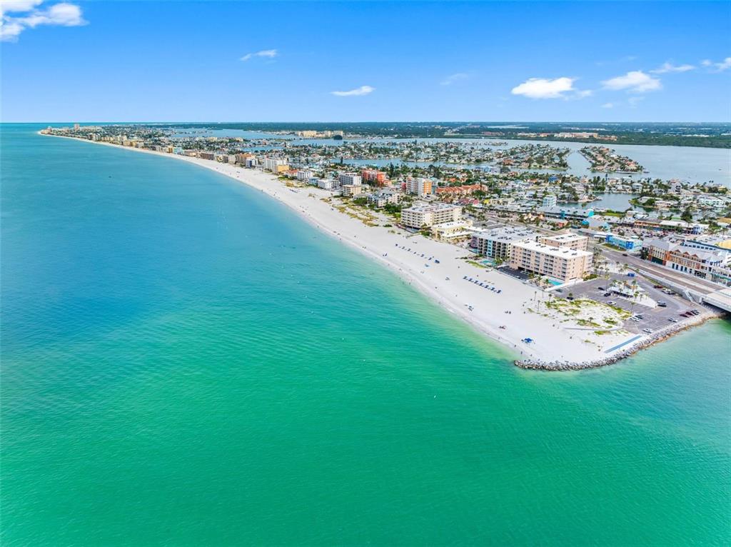 An aerial view shows a sandy beach along turquoise water with coastal buildings and homes — 12924 GULF BOULEVARD UNIT 510, MADEIRA BEACH, FL