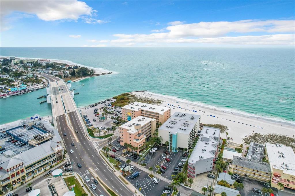 An aerial view of a coastal bridge, beach, and surrounding multi-story hotel buildings — 12924 GULF BOULEVARD UNIT 510, MADEIRA BEACH, FL