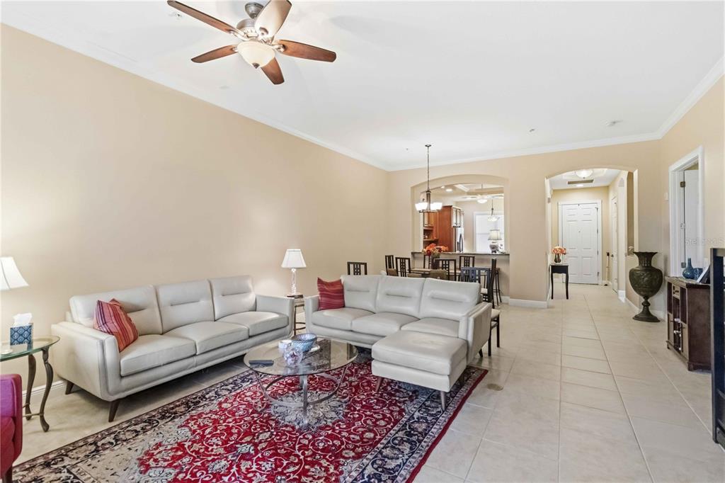 A living room with light-colored sofas, a red patterned rug, and an adjacent dining area — 5246 MANORWOOD DRIVE UNIT 4C, SARASOTA, FL