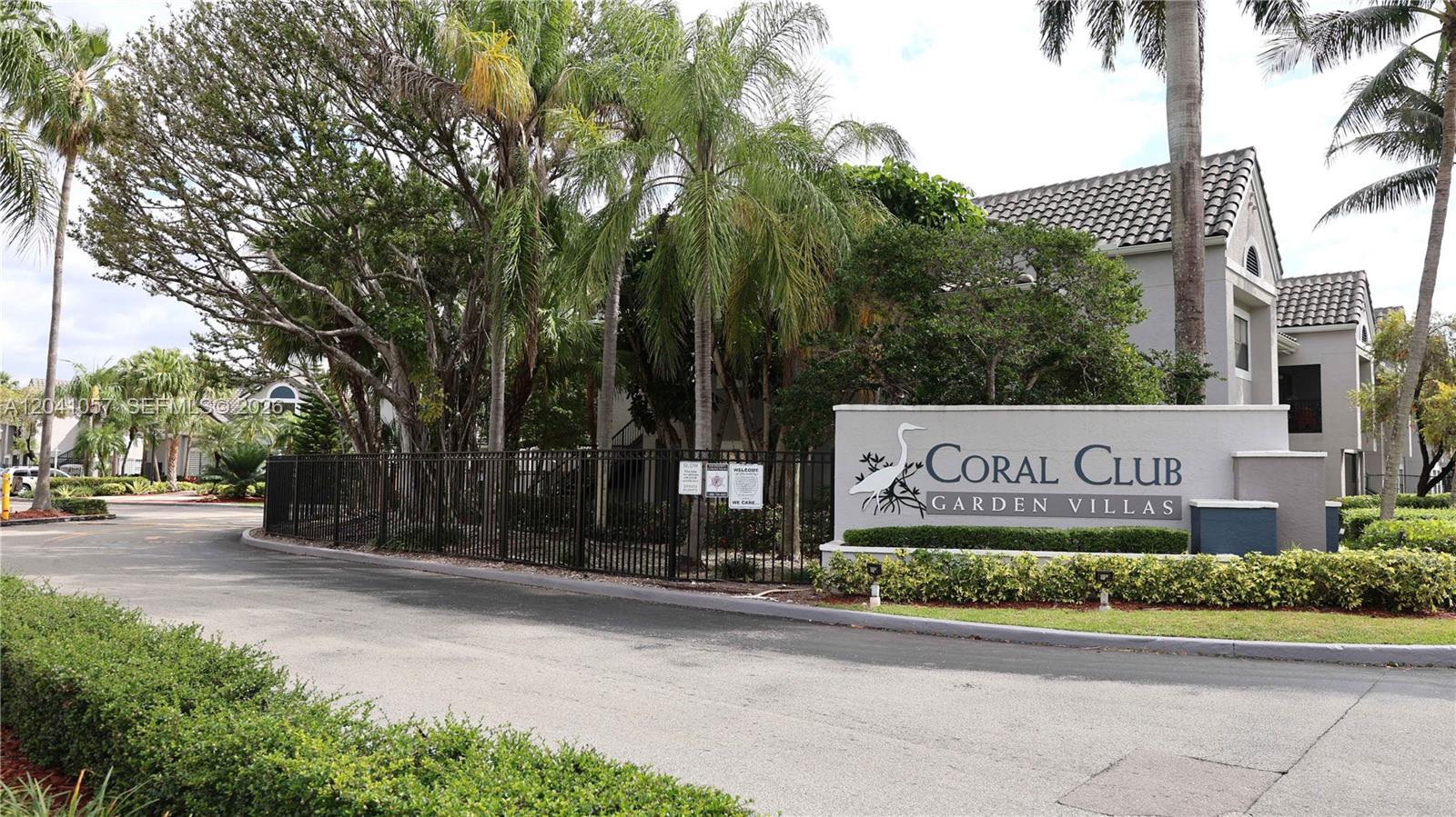The entrance sign for Coral Club Garden Villas stands beside a black metal fence — 15077 SW 103rd Ter # 8110, Miami FL 33196, MIAMI, FL