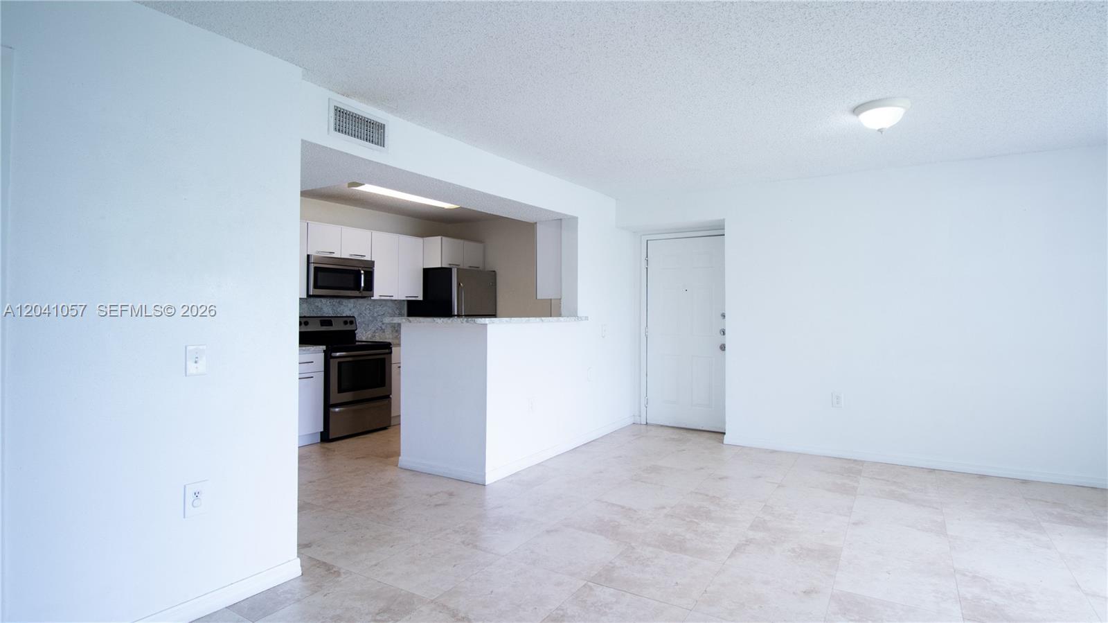 A white-walled room features a kitchen with stainless steel appliances and tile flooring — 15077 SW 103rd Ter # 8110, Miami FL 33196, MIAMI, FL