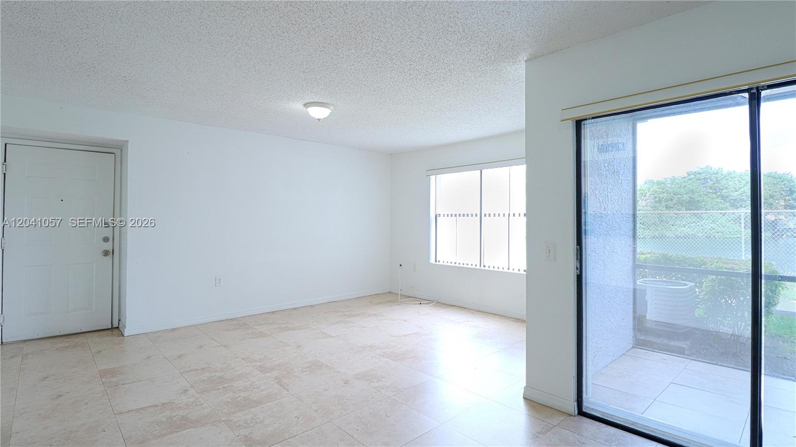 An empty room features white walls, tile flooring, a window, and a sliding glass door — 15077 SW 103rd Ter # 8110, Miami FL 33196, MIAMI, FL