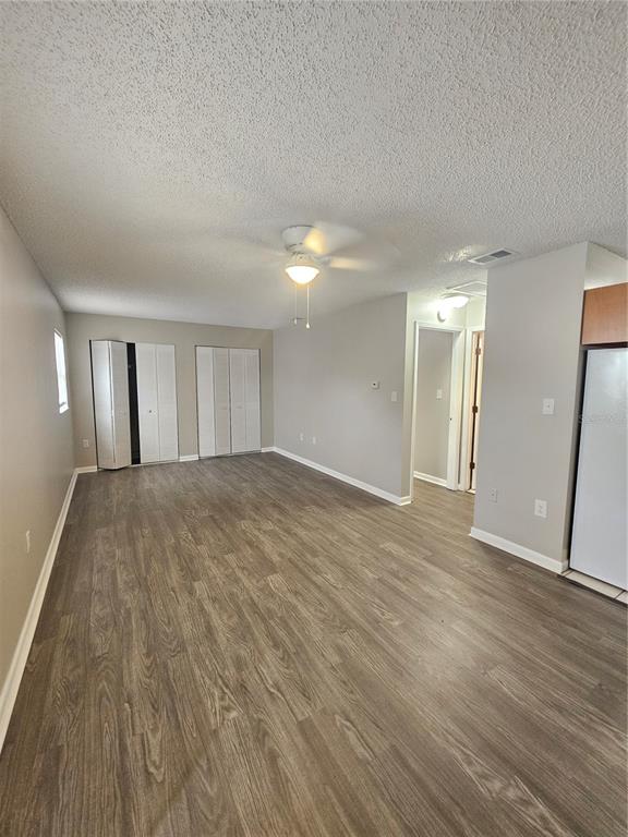 An unfurnished room with wood-look flooring, a ceiling fan, and two sets of closet doors — 455 S BUCKMOORE ROAD UNIT 78, LAKE WALES, FL
