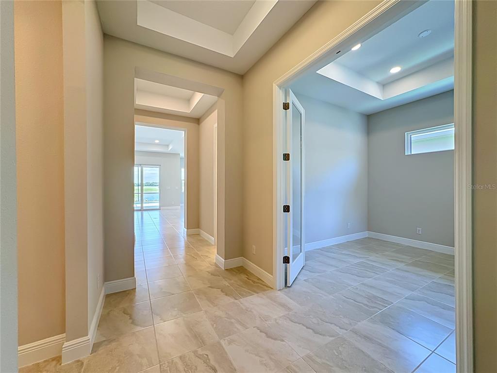 A tiled hallway leads to a room with glass French doors and a tray ceiling — 239 MONET TRAIL, BRADENTON, FL