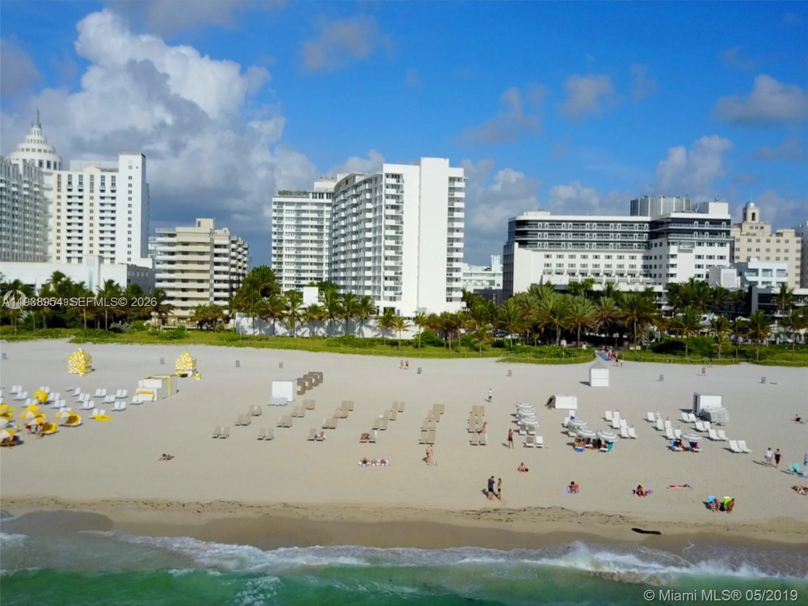 An aerial view of a sandy beach with lounge chairs and large hotels in the background — 100 Lincoln Rd # 805, Miami Beach FL 33139, MIAMI BEACH, FL
