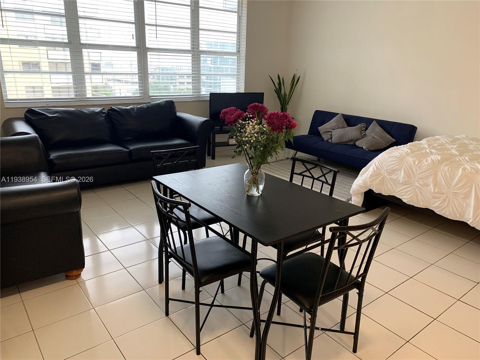 A living and dining area features tile floors, a black dining set, and two sofas — 100 Lincoln Rd # 805, Miami Beach FL 33139, MIAMI BEACH, FL