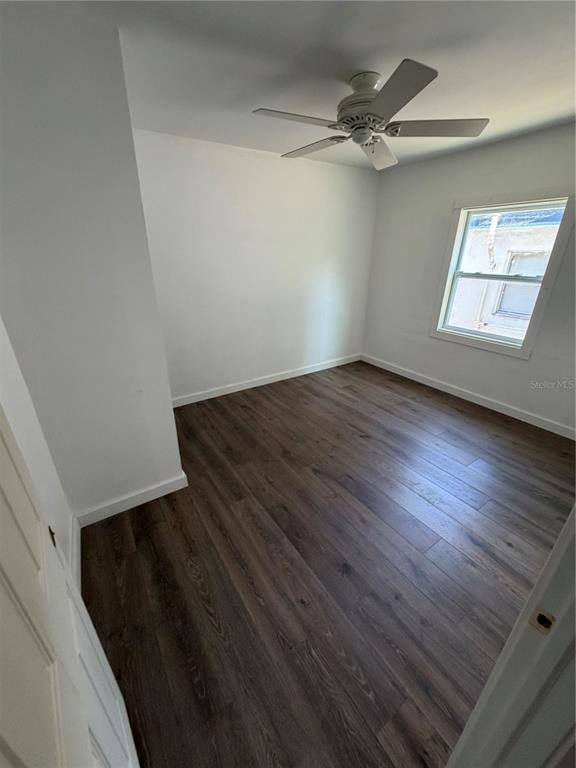 A bedroom with white walls, dark wood-look flooring, a ceiling fan, and an open closet — 911 N 21ST STREET, FORT PIERCE, FL