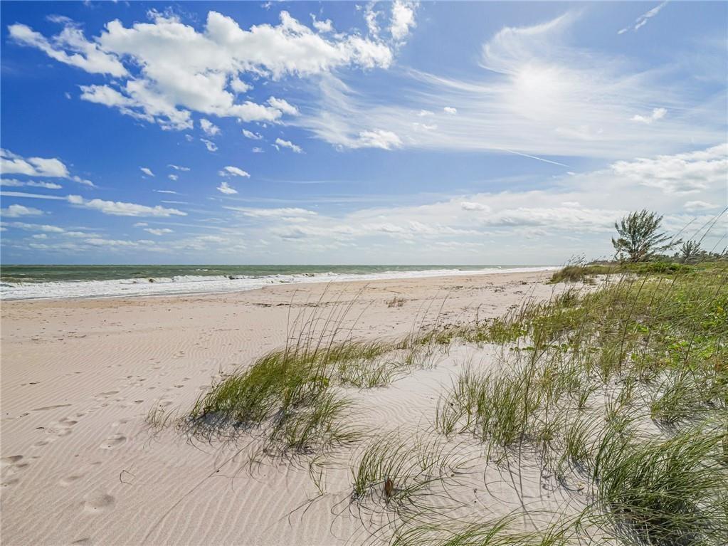 A sandy beach with dune grass leads to the ocean under a blue sky — 1330 Shorewinds Lane, Vero Beach FL 32963, VERO BEACH, FL