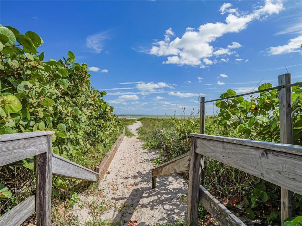 A sandy path leads through coastal vegetation toward the ocean from a wooden boardwalk — 1330 Shorewinds Lane, Vero Beach FL 32963, VERO BEACH, FL