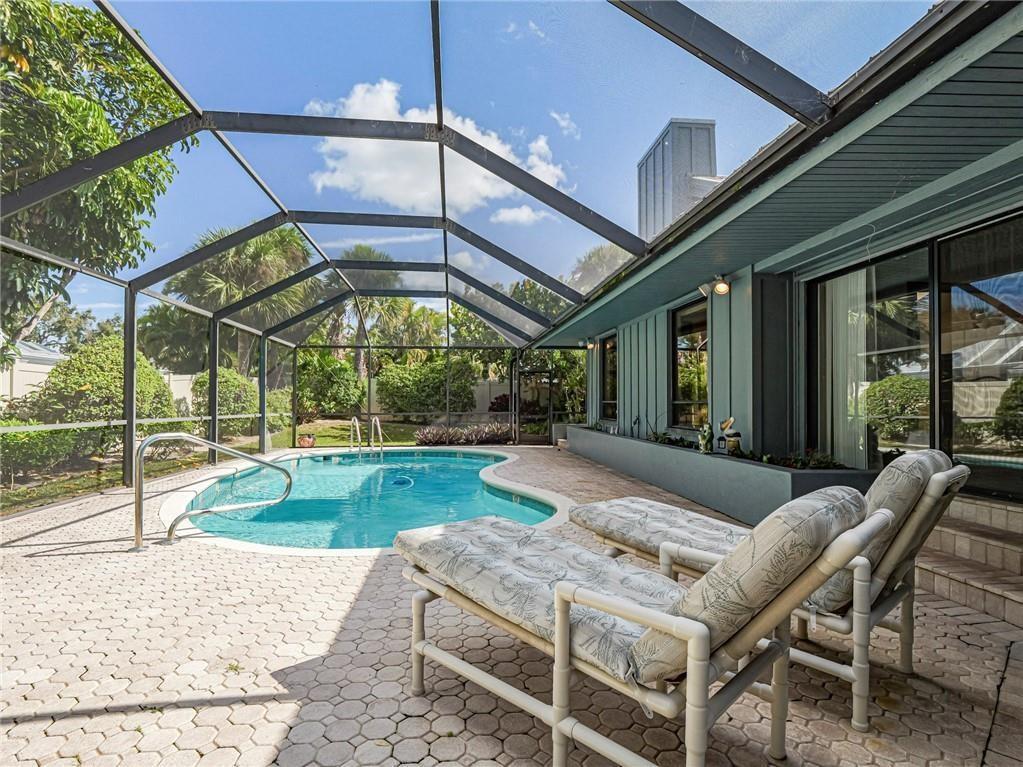 A screened-in patio features a kidney-shaped swimming pool, lounge chairs, and a paved deck — 1330 Shorewinds Lane, Vero Beach FL 32963, VERO BEACH, FL