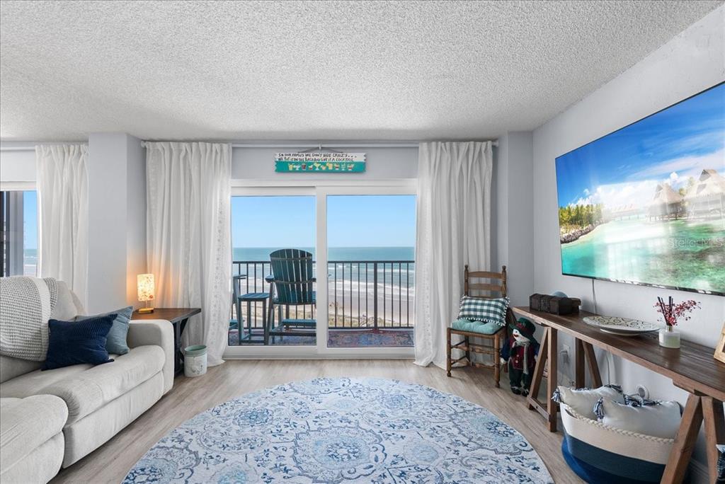 A living room features a large television, a sofa, and a balcony overlooking the ocean — 3600 S OCEAN SHORE BOULEVARD UNIT 712, FLAGLER BEACH, FL