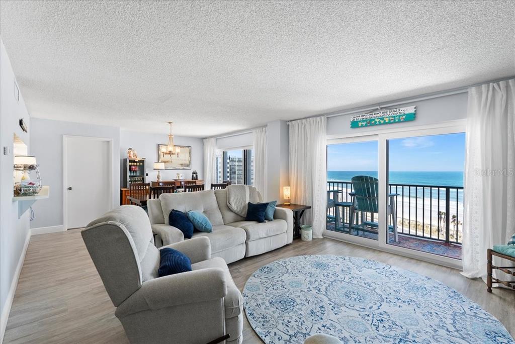 A living room with light wood floors, a sofa, a recliner, and a balcony overlooking the ocean — 3600 S OCEAN SHORE BOULEVARD UNIT 712, FLAGLER BEACH, FL