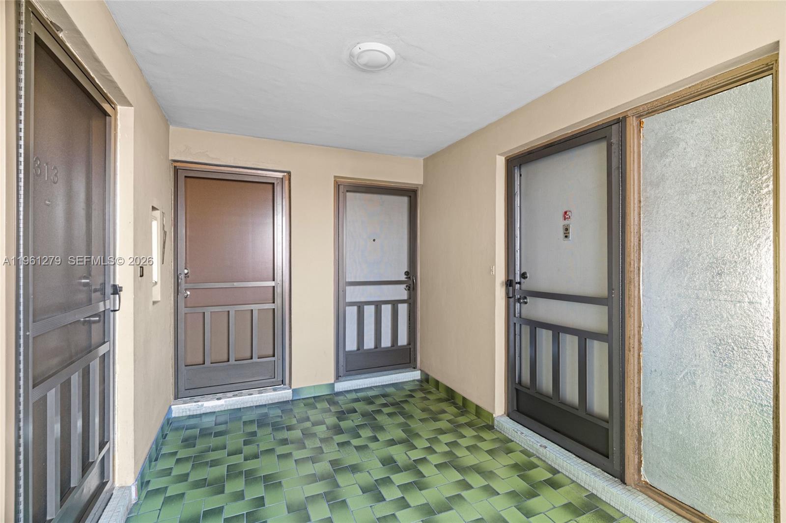 An outdoor entryway features green tiled flooring and three doors with screen storm doors — 1690 NE 191st St # 1, Miami FL 33179, MIAMI, FL
