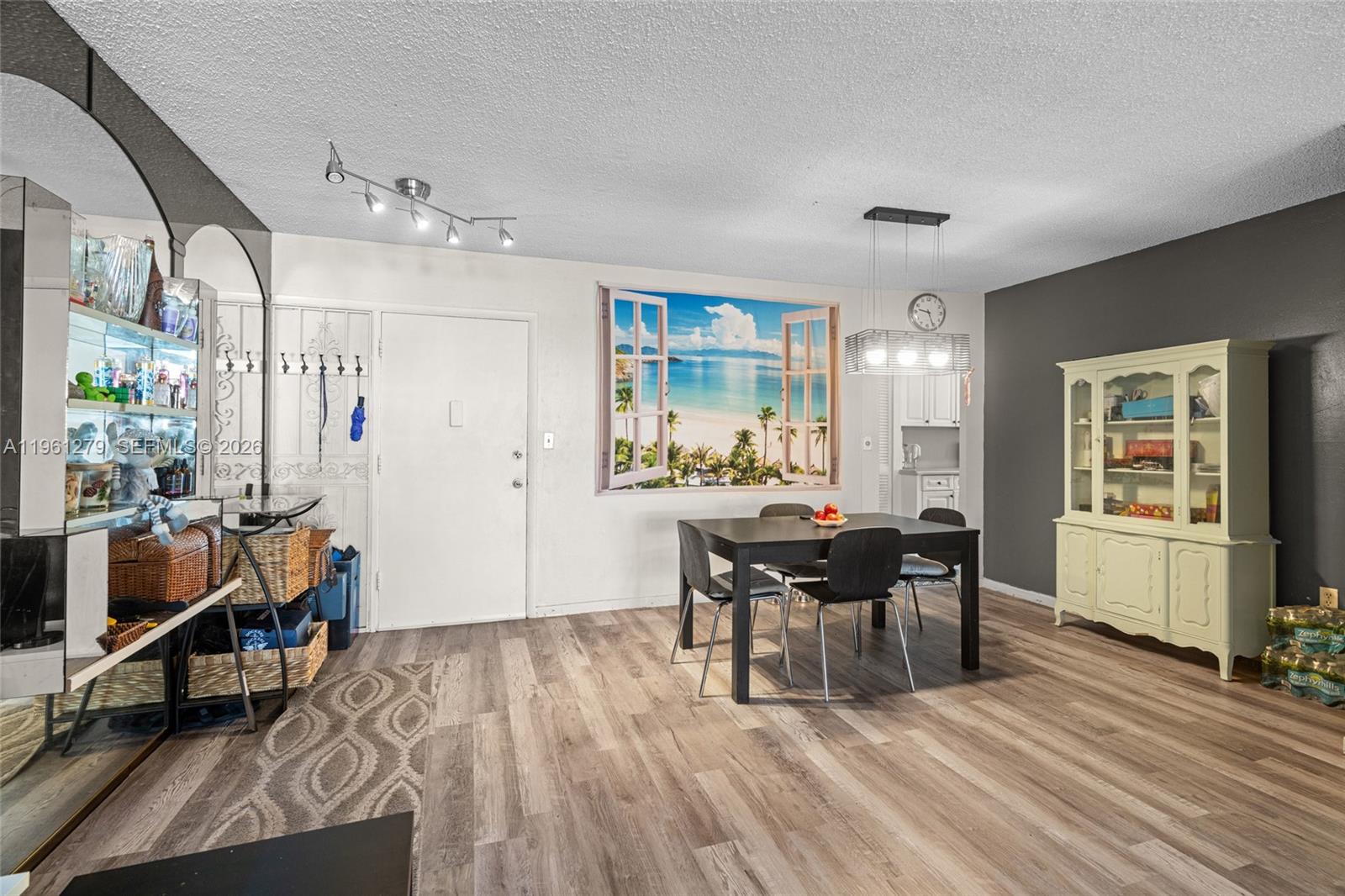 A dining area features wood-look flooring, a beach-themed wall mural, and a light-colored hutch — 1690 NE 191st St # 1, Miami FL 33179, MIAMI, FL