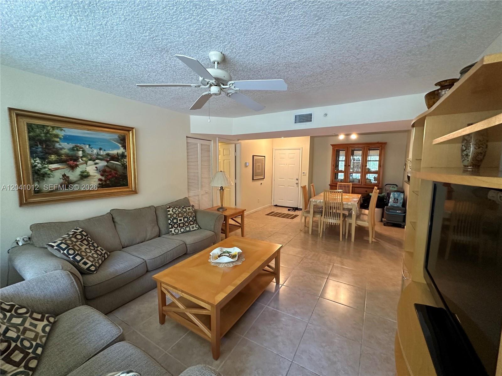 A living room features a gray sofa, a wooden coffee table, and a dining area — 619 E Sheridan St # 105, Dania Beach FL 33004, DANIA BEACH, FL