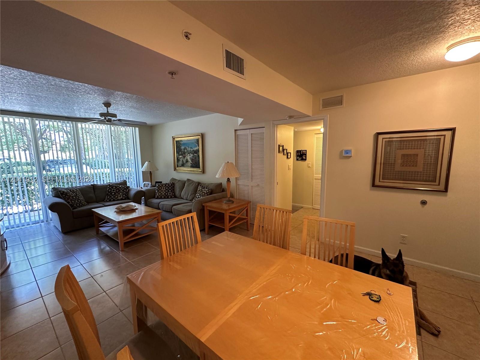 A dining area with a wooden table sits in front of a living room — 619 E Sheridan St # 105, Dania Beach FL 33004, DANIA BEACH, FL