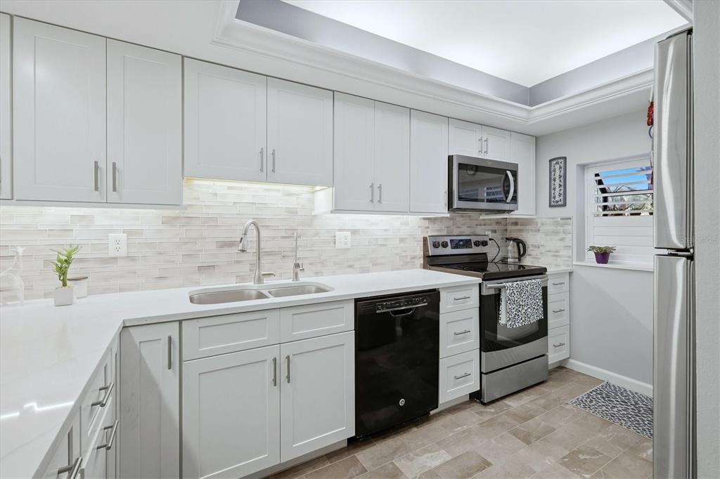 A kitchen with light gray cabinets, white countertops, a tiled backsplash, and stainless steel appliances — 3361 CROSS CREEK DRIVE UNIT 3361, SARASOTA, FL