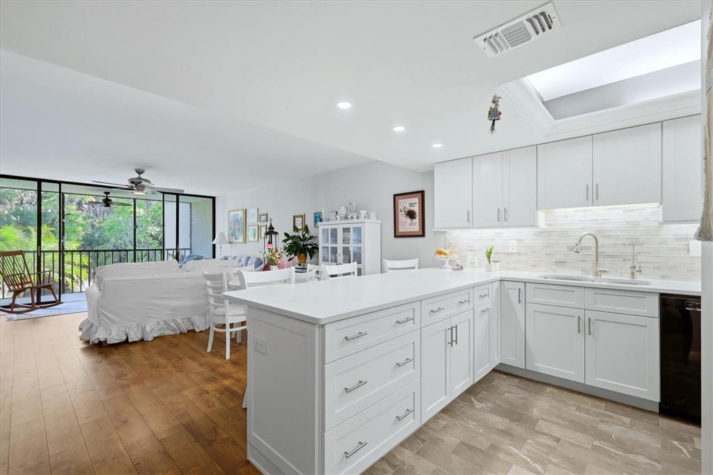 A bright kitchen with white cabinets and a quartz island opens to a living area — 3361 CROSS CREEK DRIVE UNIT 3361, SARASOTA, FL