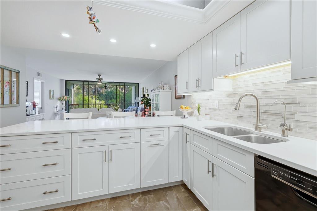 A white kitchen with quartz countertops and a stainless steel sink overlooks a living area — 3361 CROSS CREEK DRIVE UNIT 3361, SARASOTA, FL