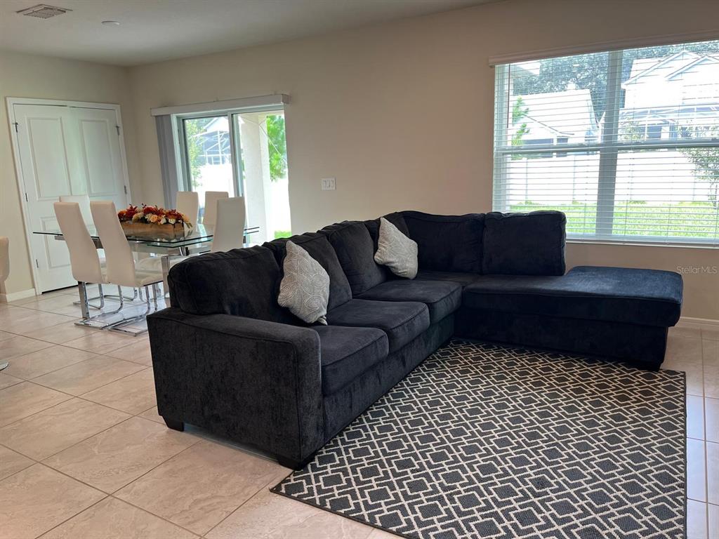 A living room with a dark sectional sofa and a dining area with a glass table — 893 RIVERS CROSSING STREET, CLERMONT, FL