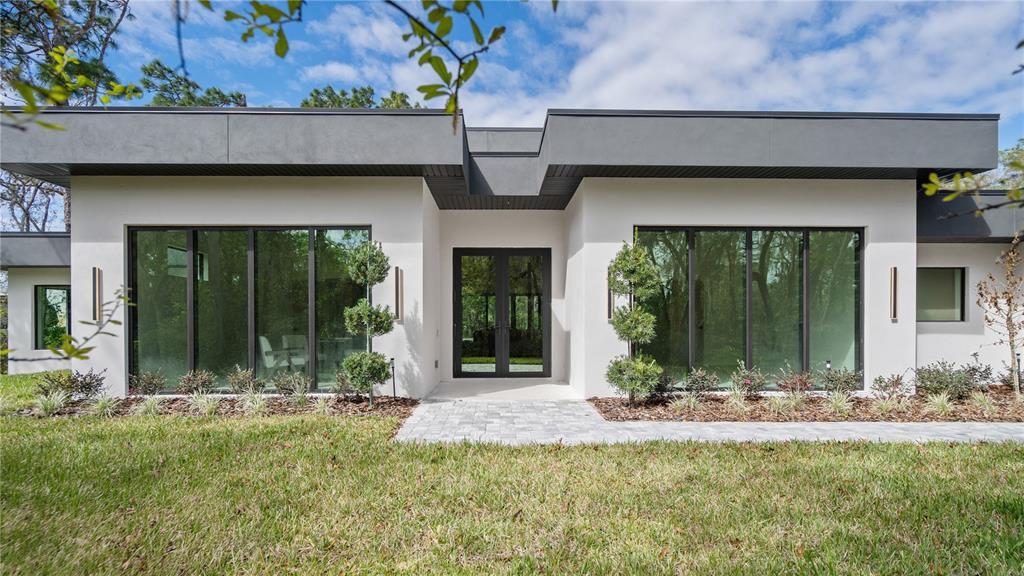 A modern, single-story house with a flat roof, white stucco walls, and large glass windows — 1447 BIRD ROAD, WINTER SPRINGS, FL