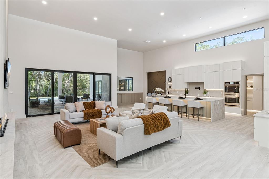 A modern open-concept living room and kitchen featuring light wood floors and large glass doors — 1447 BIRD ROAD, WINTER SPRINGS, FL