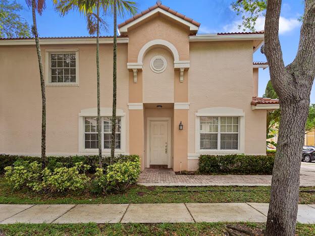 A two-story tan stucco building features a central arched entryway and a paved walkway — 12444 SW 42nd Street, Miramar FL 33027, MIRAMAR, FL