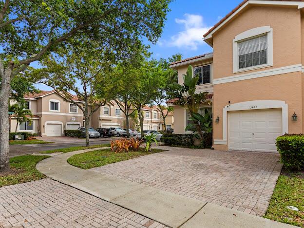 A two-story tan house with a brick driveway and a white garage door — 12444 SW 42nd Street, Miramar FL 33027, MIRAMAR, FL