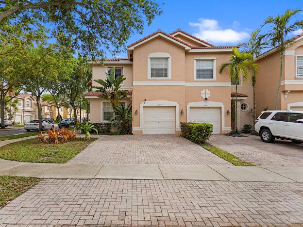 A two-story tan townhouse with a brick paver driveway and a white SUV parked outside — 12444 SW 42nd Street, Miramar FL 33027, MIRAMAR, FL